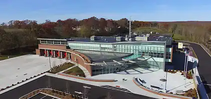 A modern building with glass walls and bulletproof windows features an entrance canopy and red garage doors.